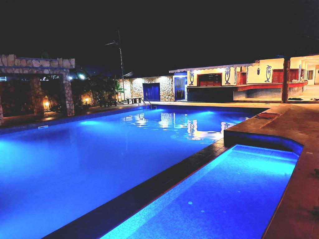 a swimming pool lit up at night with blue lights at Blue Palm Resort Ghana in Abia