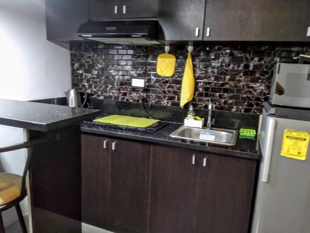a kitchen with a sink and a refrigerator at ADB Tower 1 bedroom with fast wifi and Netflix at Ortigas across Robinson's Galleria in Manila