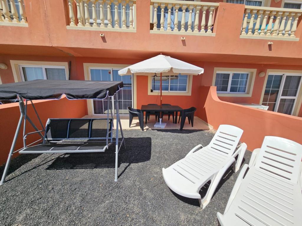 une terrasse avec une table, des chaises et un parasol dans l'établissement Your Ocean Blue, à Costa Calma