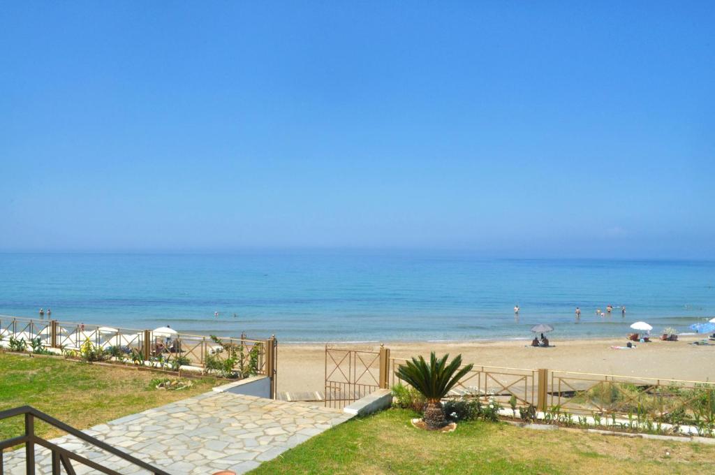 a beach with people on the sand and the ocean at Beachfront 4-bed luxury suite - Agios Gordios, Corfu, Greece in Agios Gordios