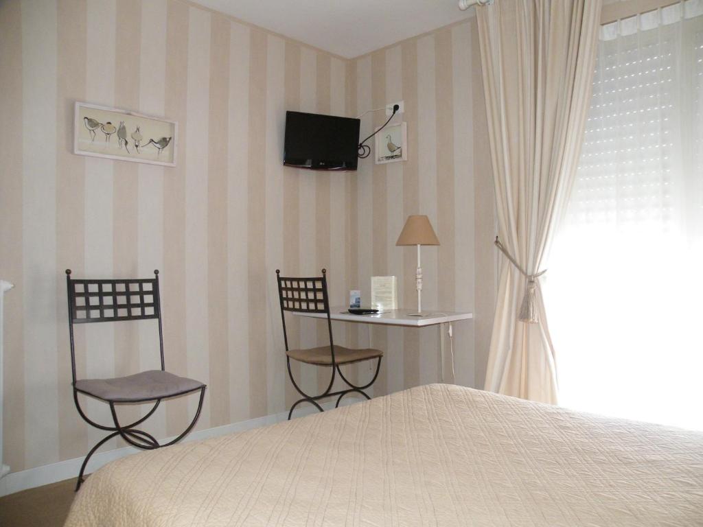 a bedroom with a bed and two chairs and a tv at Hôtel de L&#39;Avenue in Saintes
