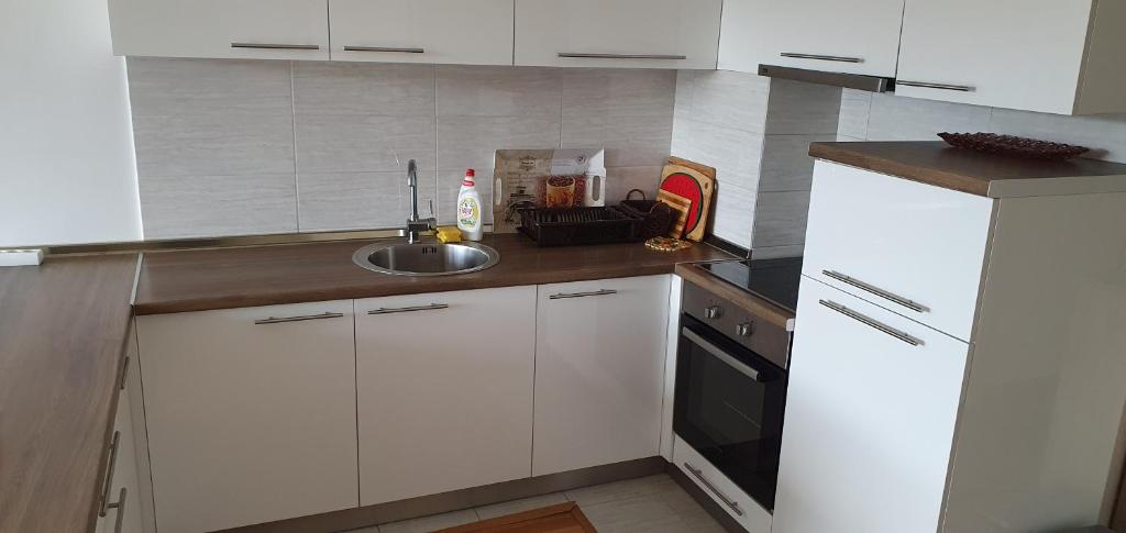 una cocina con armarios blancos y fregadero en Modern Apartment in Zenica, en Zenica