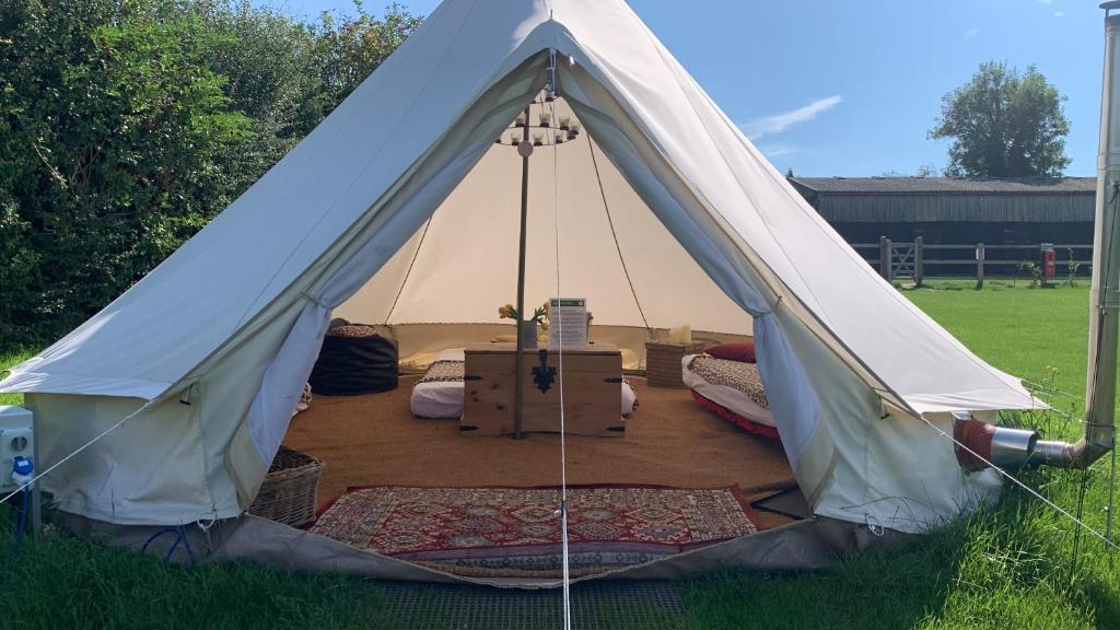 ein Tipi-Zelt mit einem Bett und Boxen auf einem Feld in der Unterkunft Home Farm Radnage Glamping Bell Tent 4, with Log Burner and Fire Pit in Radnage