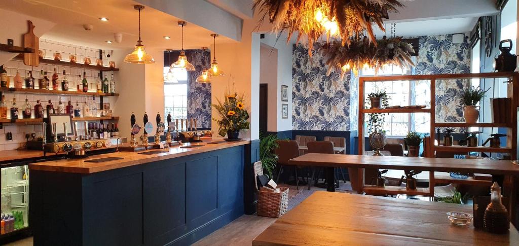 eine Bar in einem Restaurant mit einer Holztheke und Tischen in der Unterkunft Ensuite Bed And Breakfast Rooms At The Ring Pub in Gwredog