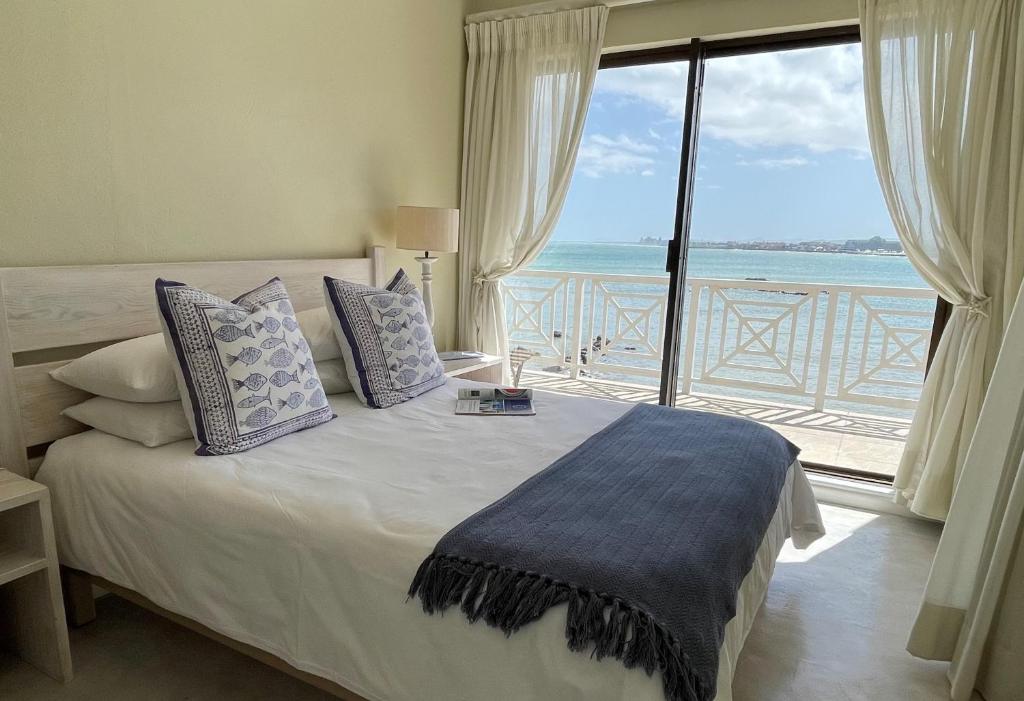 a bedroom with a bed with a view of the ocean at By Die See in Gordonʼs Bay