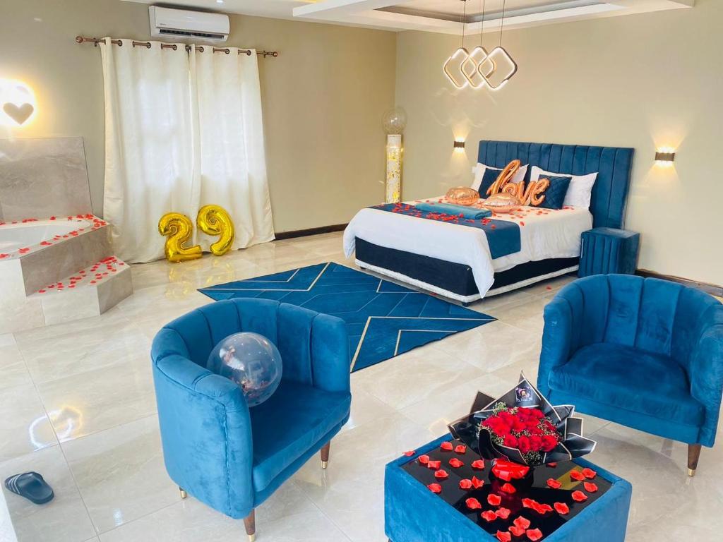 a bedroom with a bed and two blue chairs at WHITE SHARK RESORT in Ponta do Ouro