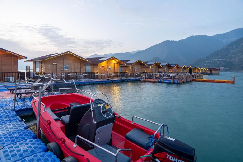 a red boat is docked at a dock with houses at Le ROI Floating Huts & Eco Rooms Tehri in Tehri-Garhwāl