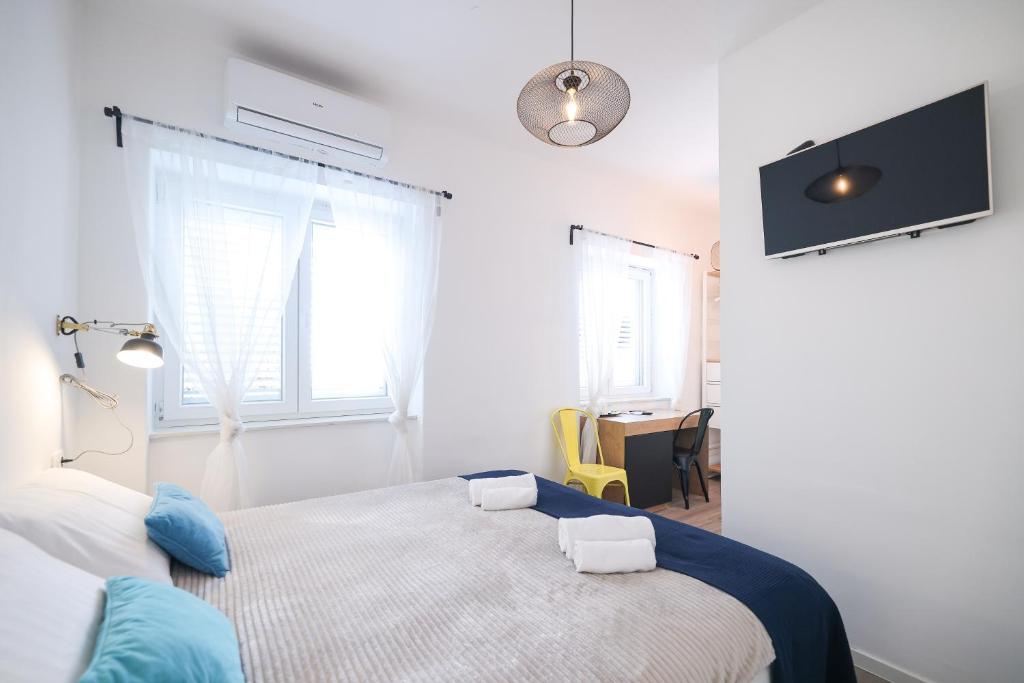 a white bedroom with a bed and a window at Rooms lopwi Old town Ground floor in Zadar