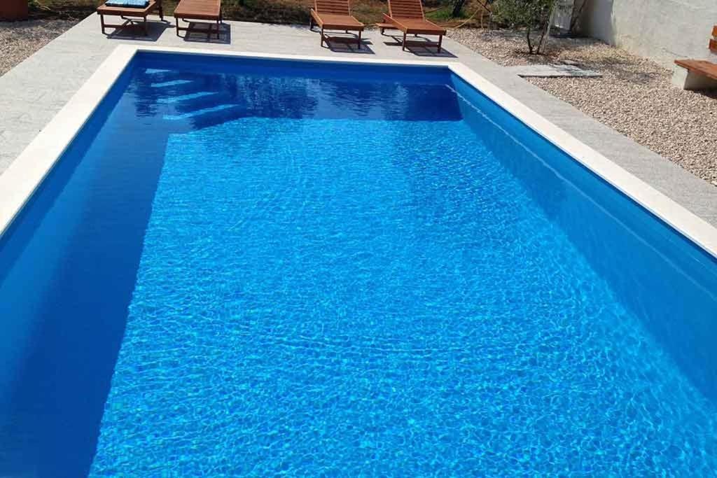 a large blue swimming pool with two chairs in it at Apartman Mia with pool1 in Split