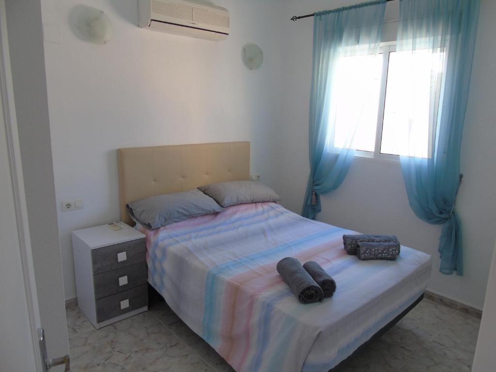 1 dormitorio con 1 cama y una ventana con cortinas azules en 2 bed Apartment Villamartin with communal pool, en San Miguel de Salinas