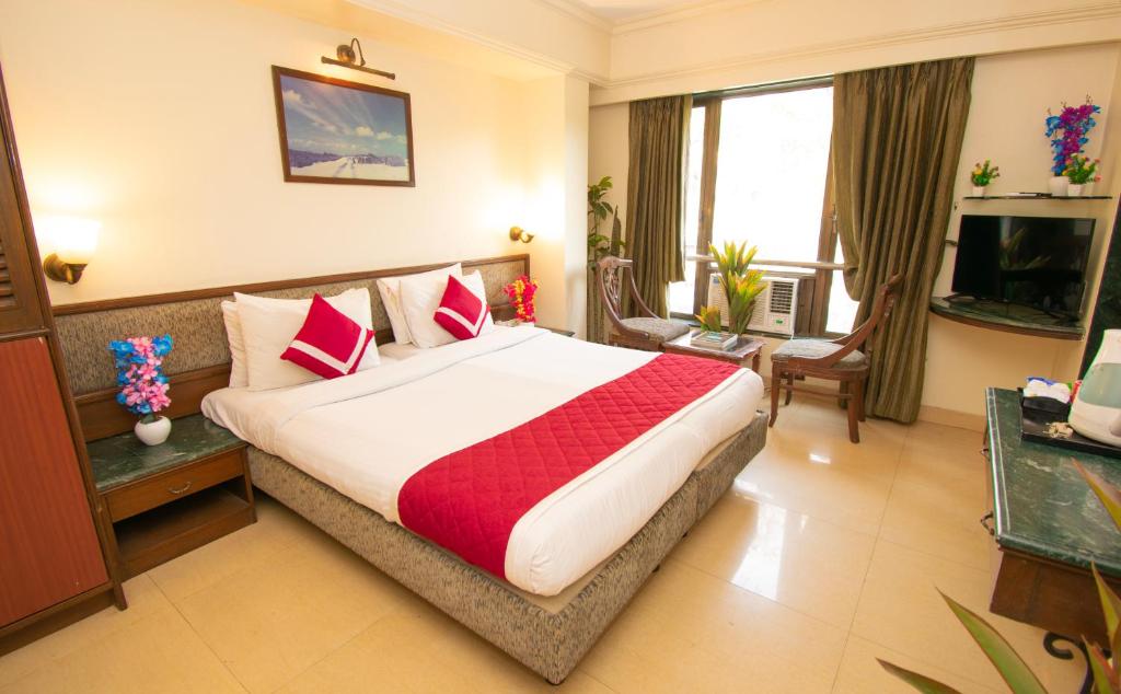 Una habitación de hotel con una cama grande y un televisor. en Octave Bund Garden, en Pune