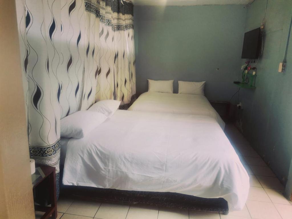 een slaapkamer met een wit bed in een kamer bij Stay Inn Krugersdorp in Krugersdorp