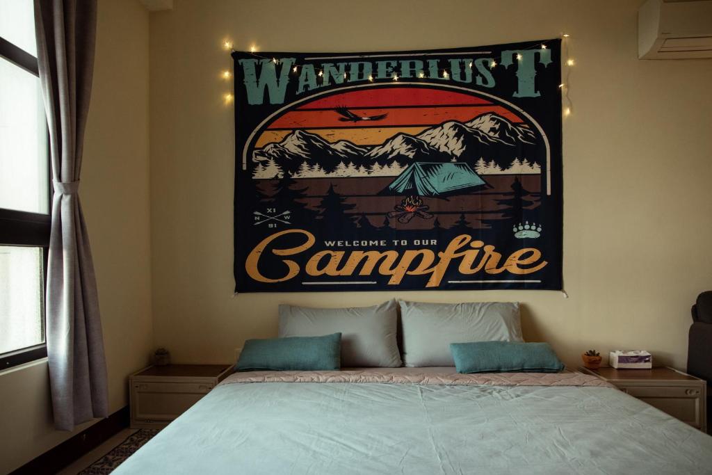 a bedroom with a bed with a poster on the wall at Bare Foot Diving Hostel 2 in Hengchun