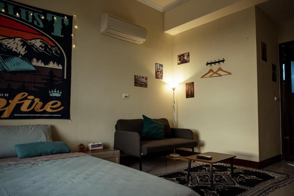 a bedroom with a bed and a couch and a lamp at Bare Foot Diving Hostel 2 in Hengchun