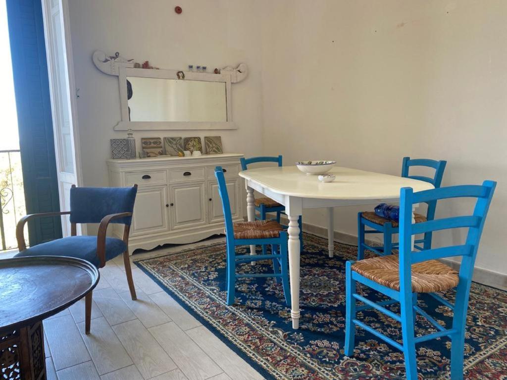 a dining room with a white table and blue chairs at casa del parco vista mare in Trapani