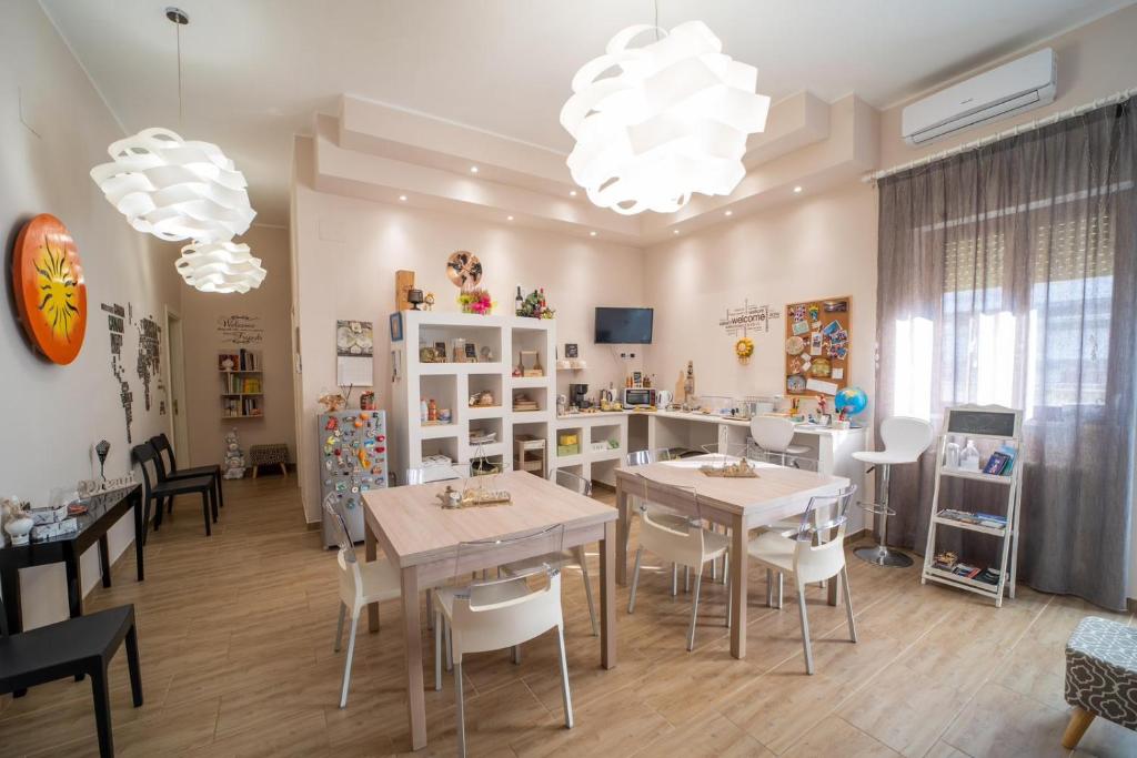 uma sala de jantar com mesas e cadeiras brancas e uma sala com janelas em Holidays Lecce em Lecce