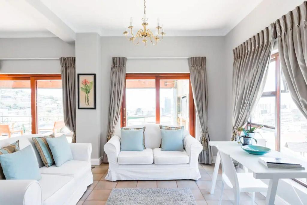 a living room with white furniture and a chandelier at 3 Bedroom Hilltop Home with Spectacular Views in Cape Town