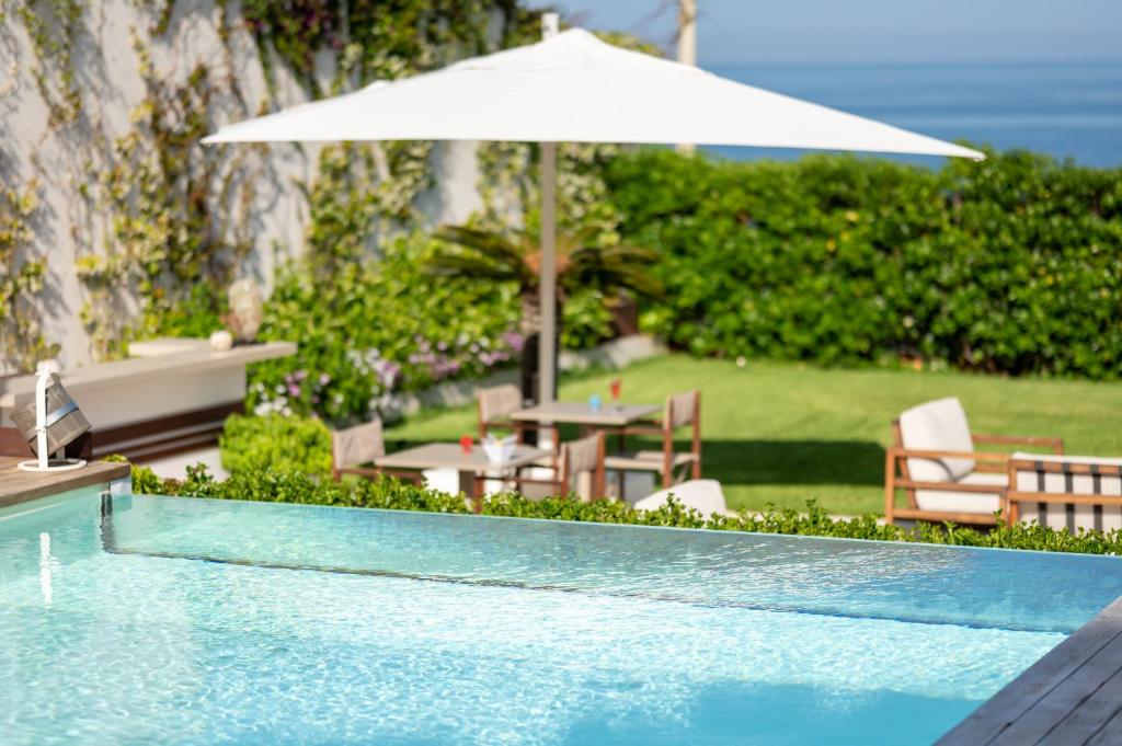a swimming pool with a table and an umbrella at Unìco Boutique Hotel d'Arte in Mondello