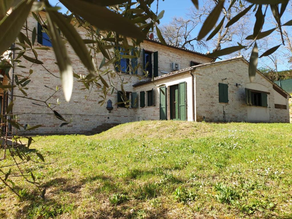 una vieja casa de ladrillo en un campo de hierba en Italian Experience-Villa Luna en Macerata