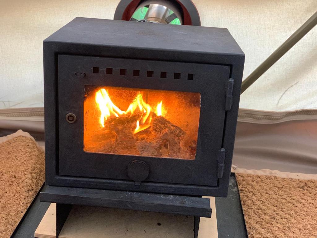 a black stove with a fire in it at Home Farm Radnage Glamping Bell Tent 3, with Log Burner and Fire Pit in Radnage