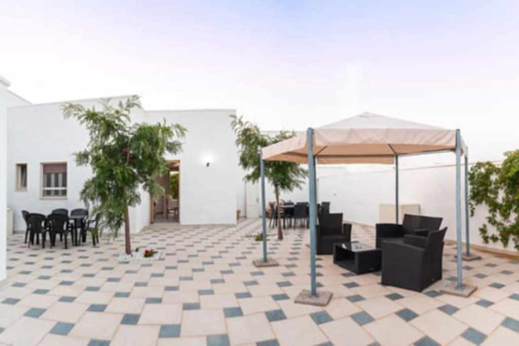 a patio with a tent and chairs and tables at Casa Tairsia in Torre Lapillo