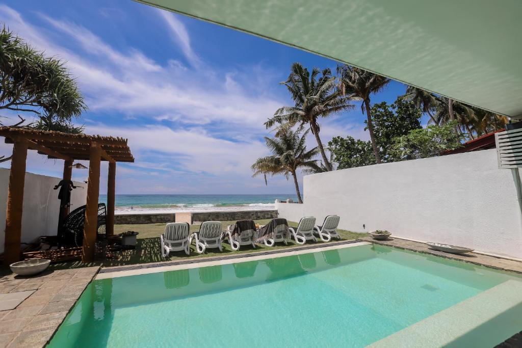 a swimming pool with chairs and the beach at Bieshu Beach Hive in Habaraduwa