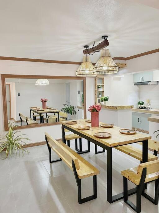 a dining room with a table and benches and a kitchen at Ba-lai homes in Baguio
