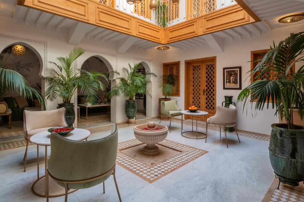 a lobby with chairs and tables and palm trees at Riad Le Saadien in Marrakech