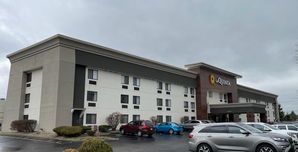 a hotel with cars parked in a parking lot at La Quinta Inn by Wyndham Indianapolis Airport Executive Dr in Indianapolis