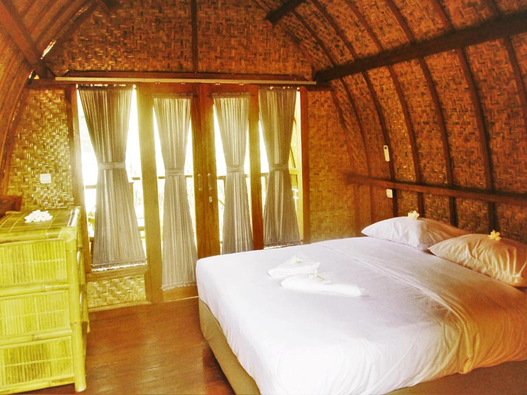 a bedroom with a large white bed with windows at Good Vibes Bungalows in Gili Trawangan