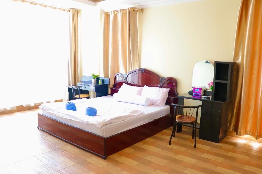 Dormitorio con cama, escritorio y TV en Gvai Apartment en Phnom Penh