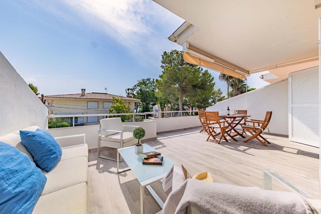 ein Wohnzimmer mit einem Sofa und einem Tisch auf dem Balkon in der Unterkunft Bon Estar Apartment in Port d'Alcúdia