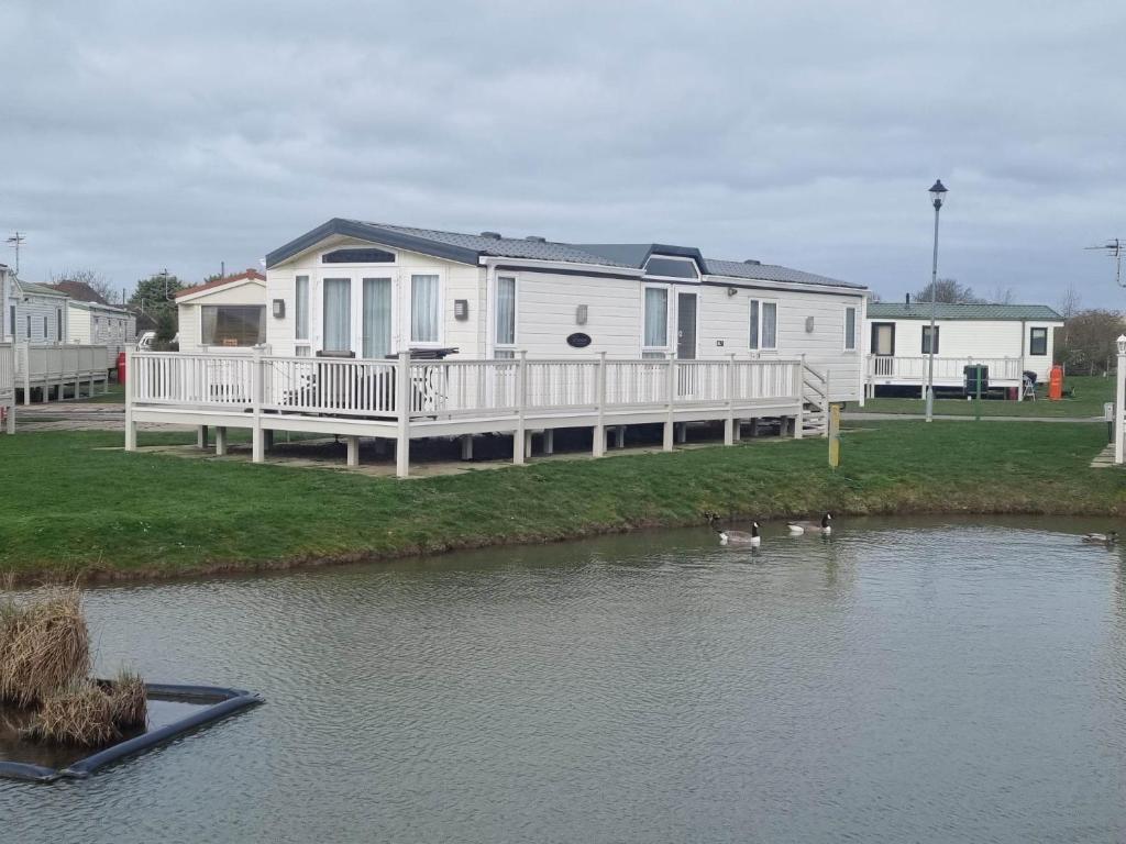 una gran casa blanca con patos en el agua en 6 BERTH DELUXE ML7 ON THE GOLDEN PALM en Chapel Saint Leonards