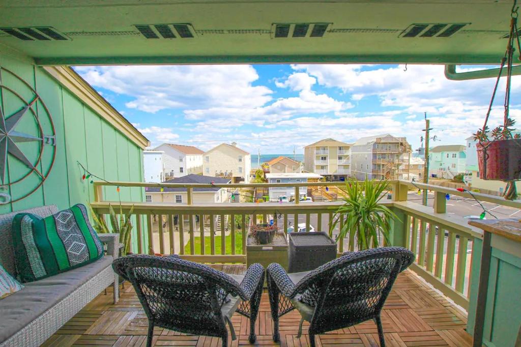 een balkon met stoelen en een bank op een terras bij Boho at the Beach in Carolina Beach