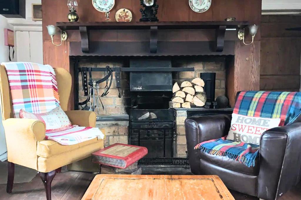 a living room with two chairs and a fireplace at Authentic Irish Cottage, Rural Ballymascanlon in Ballymascanlan