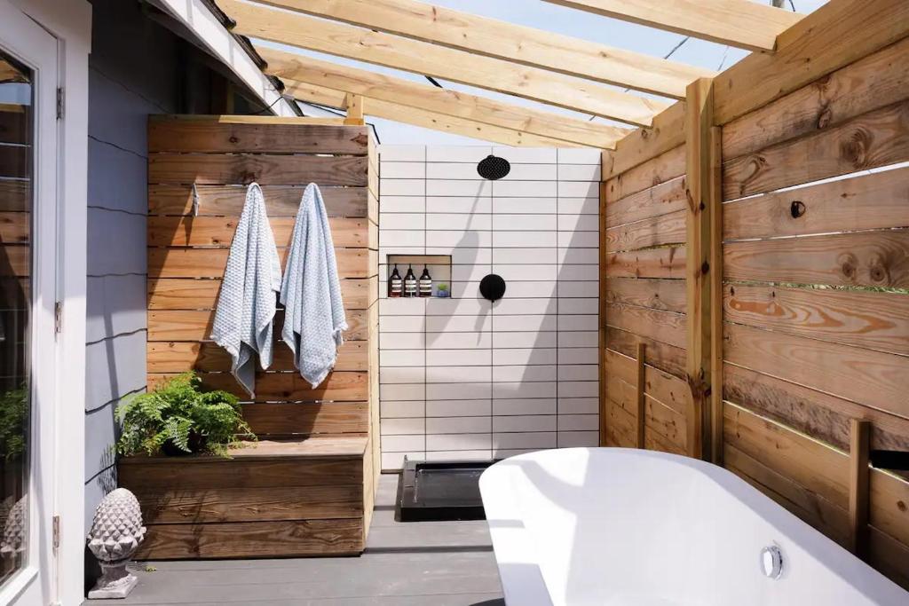 baño con bañera blanca y pared de madera en House of Kai, en Carolina Beach