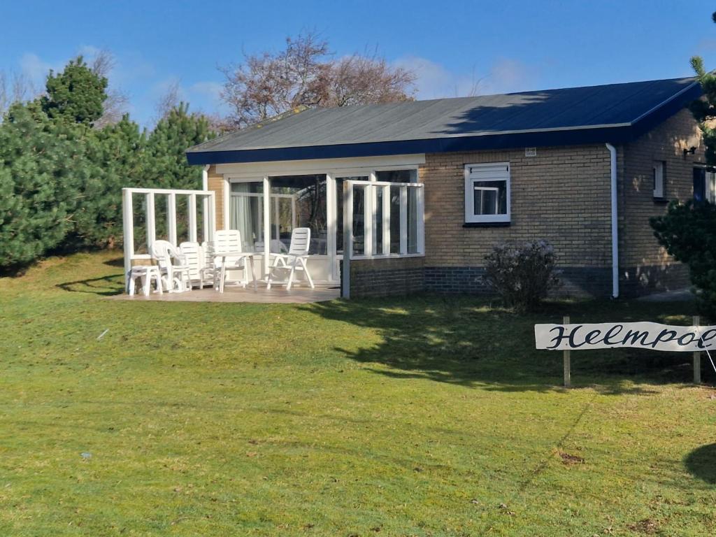 ein Haus mit einer Veranda und Stühlen auf einem Hof in der Unterkunft Helmpol in Buren