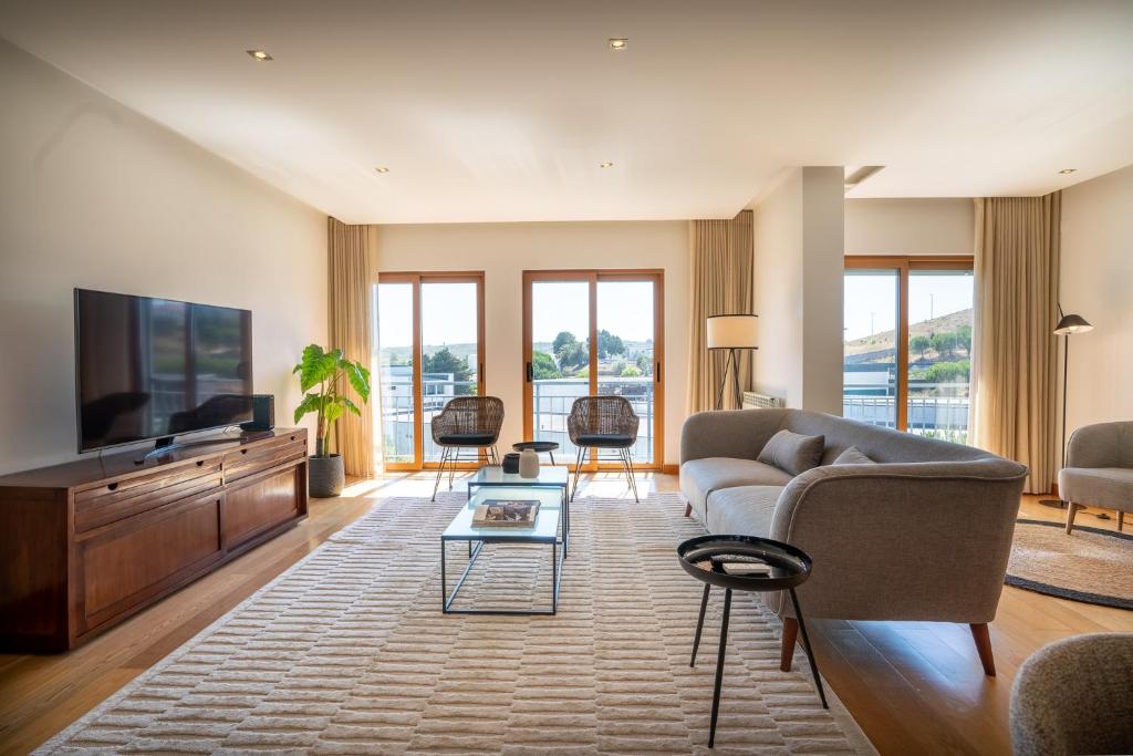 uma sala de estar com um sofá e uma televisão em Spacious and Chic Apartment with Lisbon, Sintra, or Beach at 15 min! na Amadora