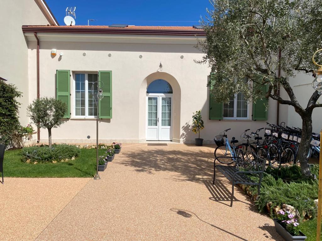 a house with green shutters and a bench in front of it at Villino Micol camere a due passi dal mare in Marina di Carrara