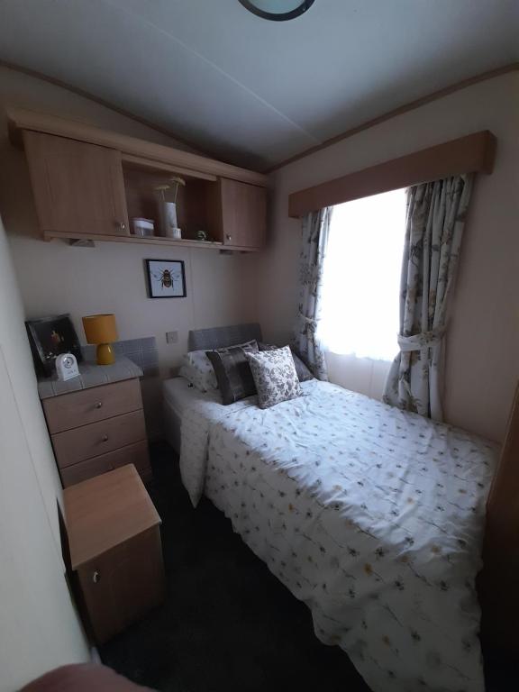 a small bedroom with a bed and a window at 3 bed caravan in Kirkcolm