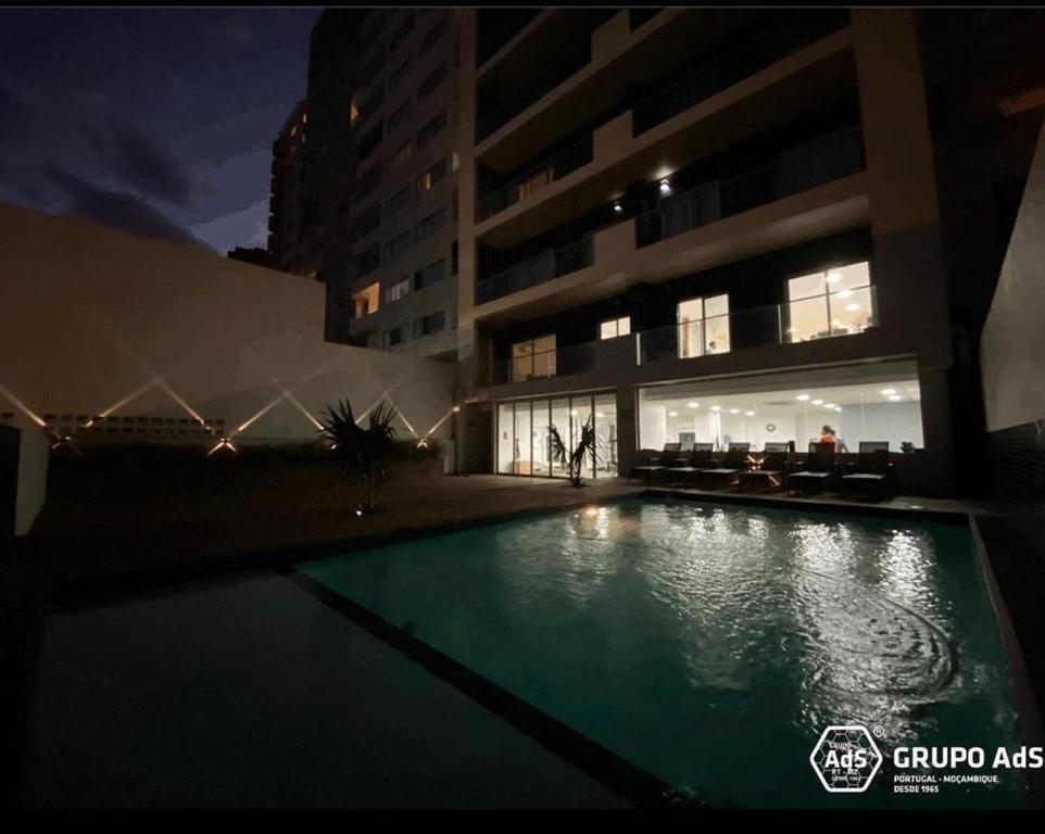 a swimming pool in front of a building at night at XENON PRIME Urban Apartments in Maputo