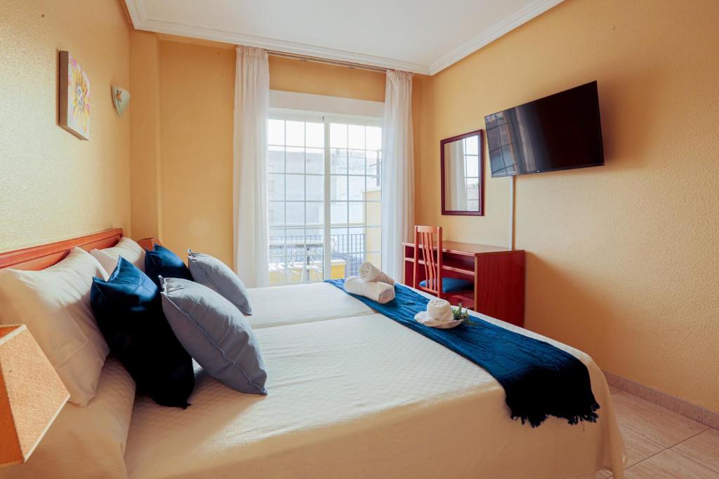 a bedroom with a large bed with a window at Hotel Tuto in Torrevieja