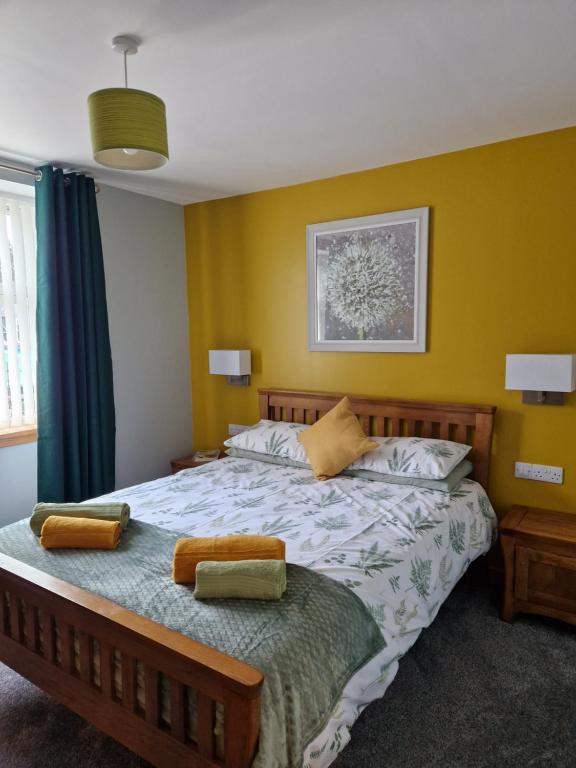a bedroom with a large bed with yellow walls at Deeside Holiday Cottages in Dinnet