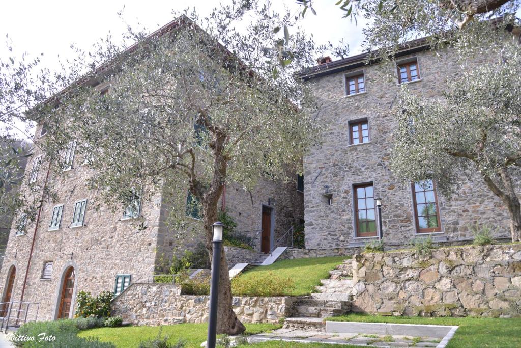 un grand bâtiment en pierre avec des arbres devant lui dans l'établissement Locanda Il Monastero, à Ortonovo