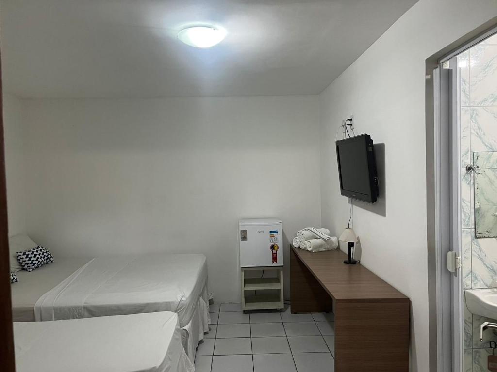 a small room with two beds and a tv at Jampa Mar Pousada in João Pessoa