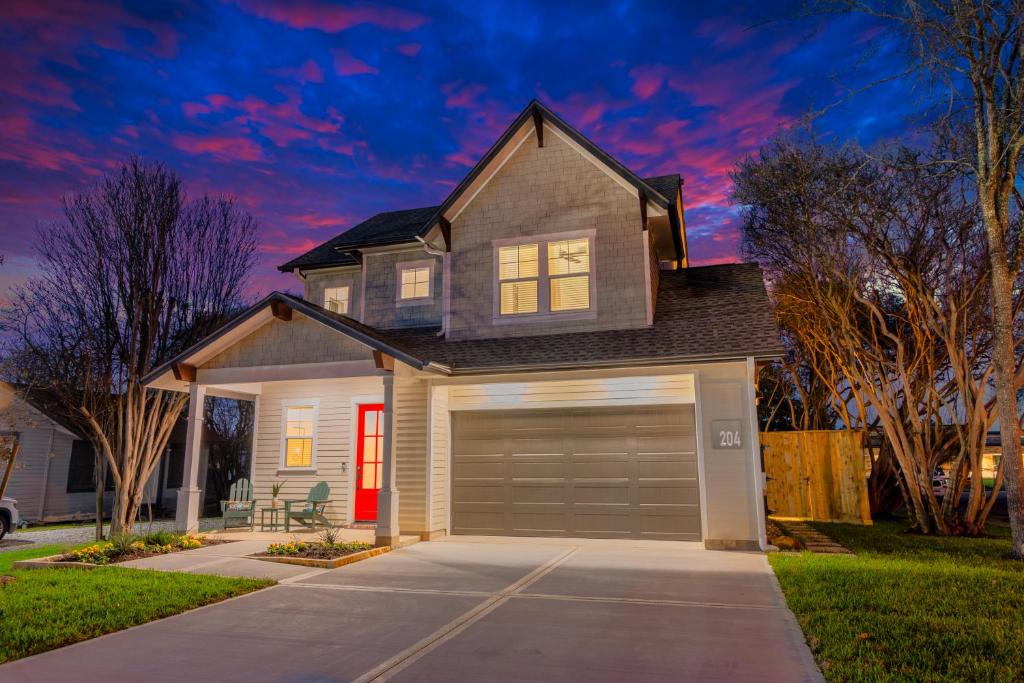 a house with a garage at dusk at The Lodge Uptown Conroe in Conroe