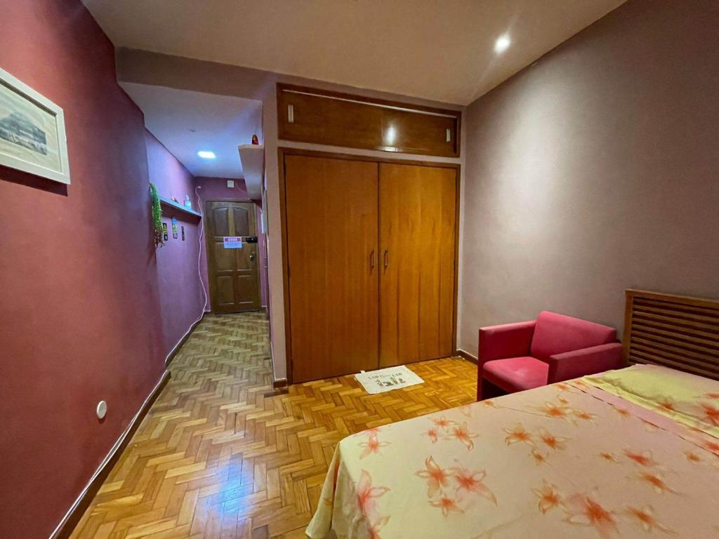 um quarto de hotel com uma cama e uma cadeira rosa em Loft 601 no Rio de Janeiro