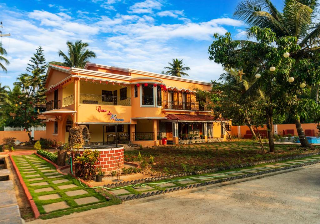 a yellow building with palm trees in front of it at Casa de Alnena in Benaulim