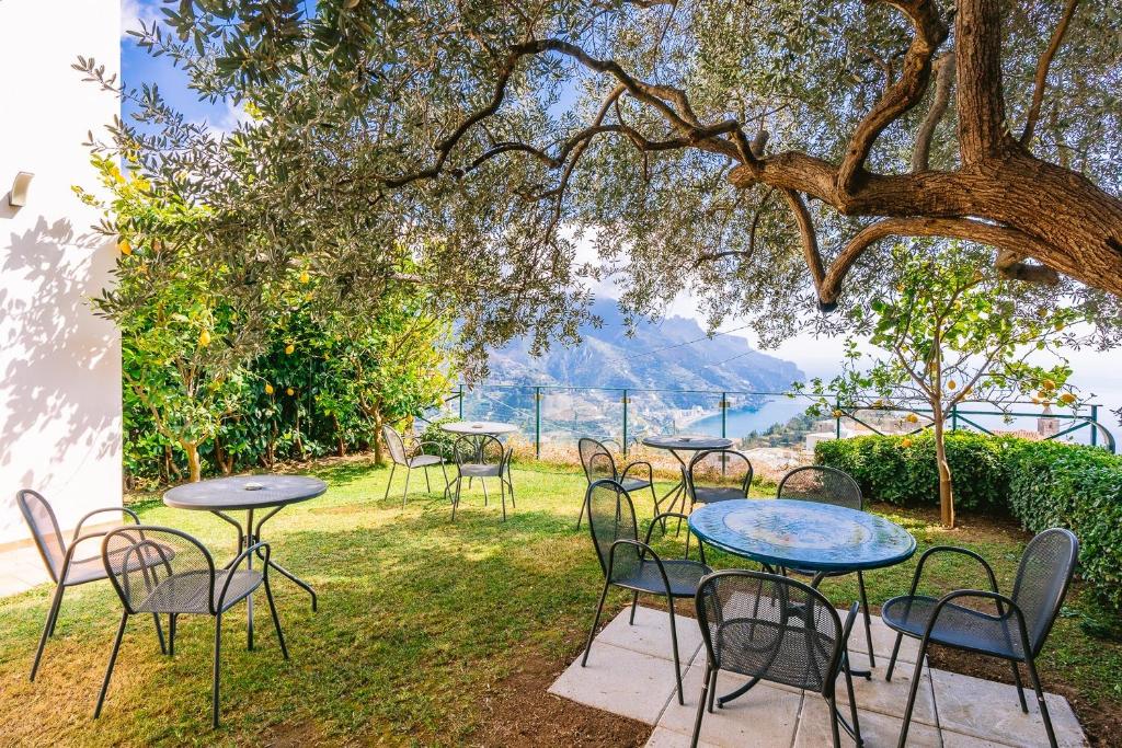 um grupo de mesas e cadeiras debaixo de uma árvore em Al Borgo Torello em Ravello