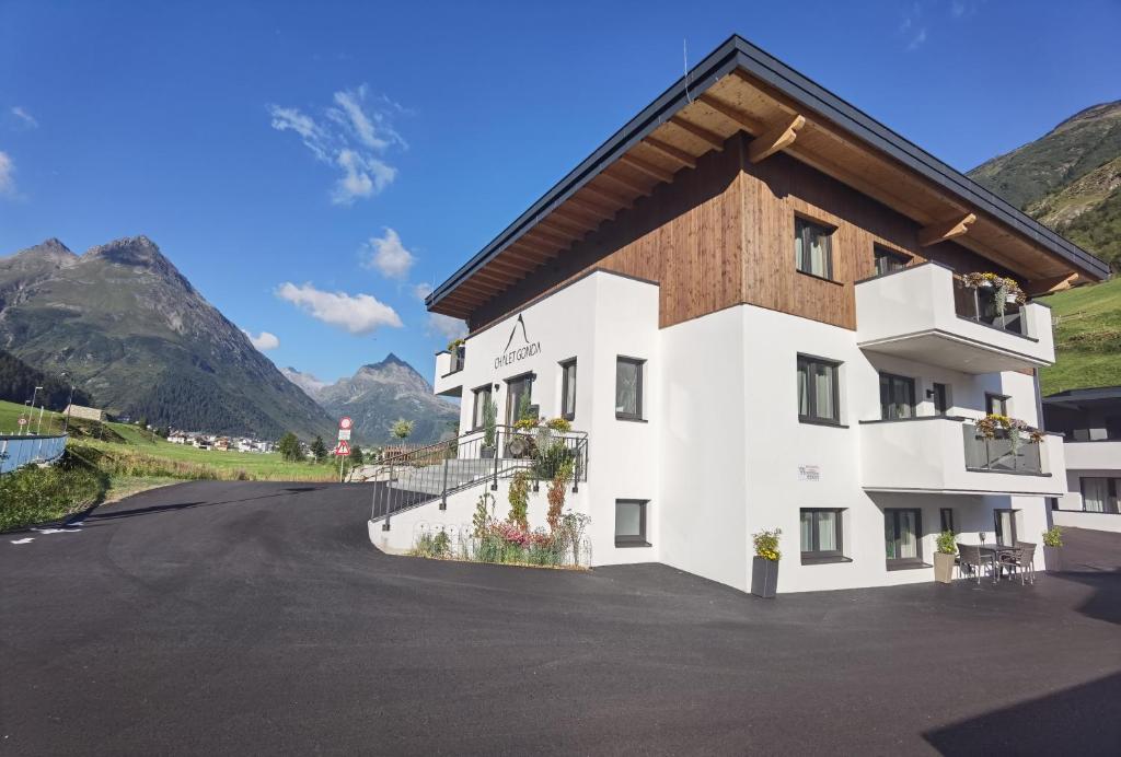 a building on a road with mountains in the background at Chalet Gonda inklusive Premiumcard in Galtür